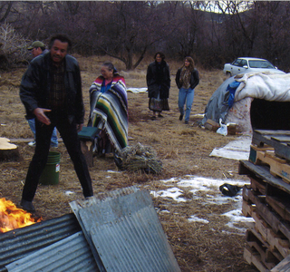 A group of men standing around a fire at sweat lodge and supporters reunion in 2002