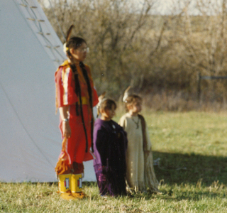 Mary Gopher and two children in front of teepee