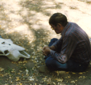 Robert Gopher sitting on the ground meditating in front of a buffalo skull